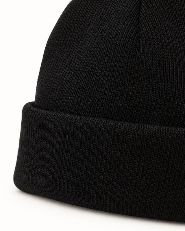 Black beanie knit and folded cuff Reference illustration: Close-up of a black knitted beanie showing the crown texture and folded cuff.