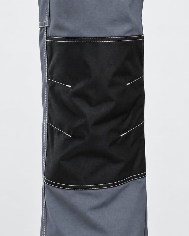 Reference illustration of a black knee panel with white edge stitching on grey work pants.