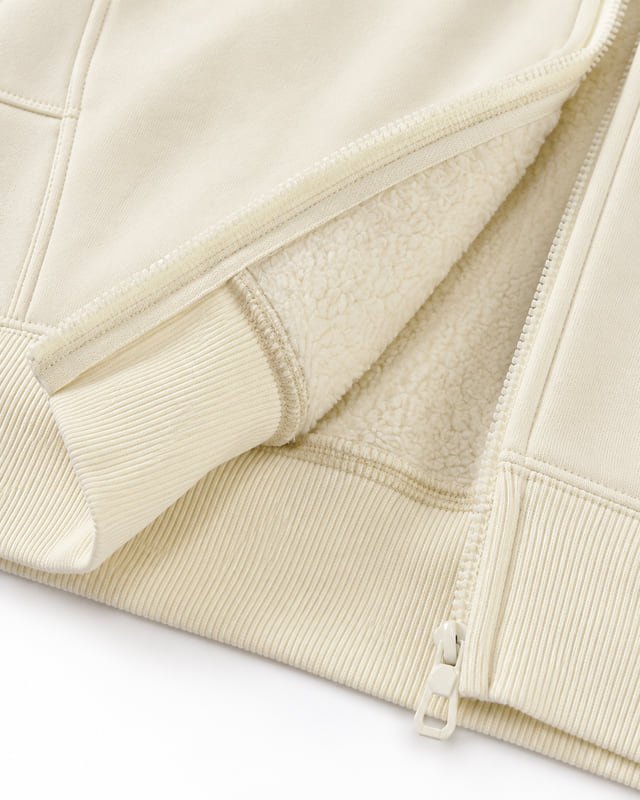 Cream sweatshirt with sherpa-textured lining Reference illustration: Close-up of a cream zip sweatshirt opened to show a textured pile lining, ribbed edges and front zip.