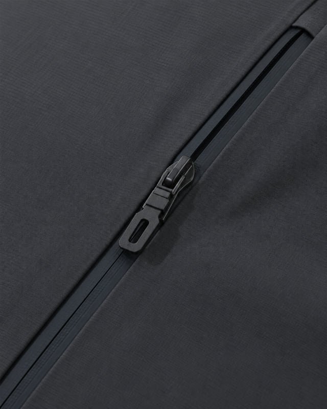Reference illustration of a diagonal dark zip pocket and pull on charcoal jacket fabric.