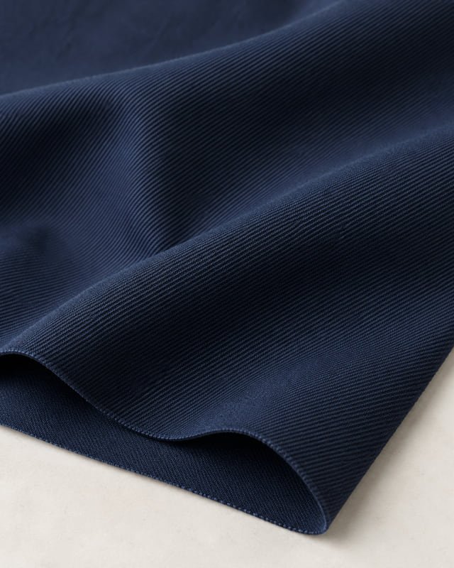 Navy fine-twill fabric reference Reference illustration of navy fabric with fine diagonal twill lines and a folded edge.