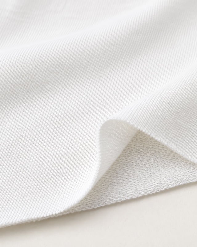 White jersey fabric — face and reverse Reference illustration: White jersey fabric with a folded corner showing its fine knit face and reverse.